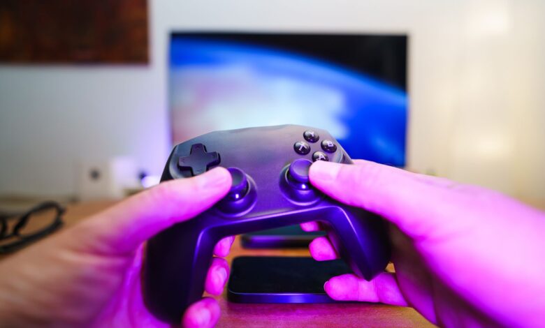 Close-up of hands holding a game controller in front of a TV screen. Perfect for entertainment setups.