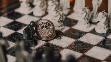 Close-up of a detailed chess set inspired by fantasy themes with a magical vintage clock on the board.