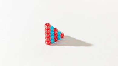 Stacked red and blue dice form a pyramid on a white background, casting a shadow.