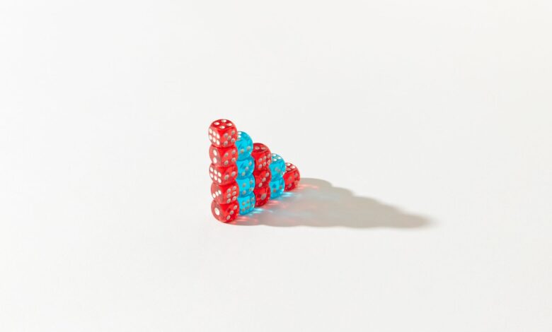 Stacked red and blue dice form a pyramid on a white background, casting a shadow.