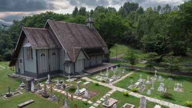 Scenic aerial view of All Saints Church surrounded by lush greenery and cemetery in Taiping, Malaysia.