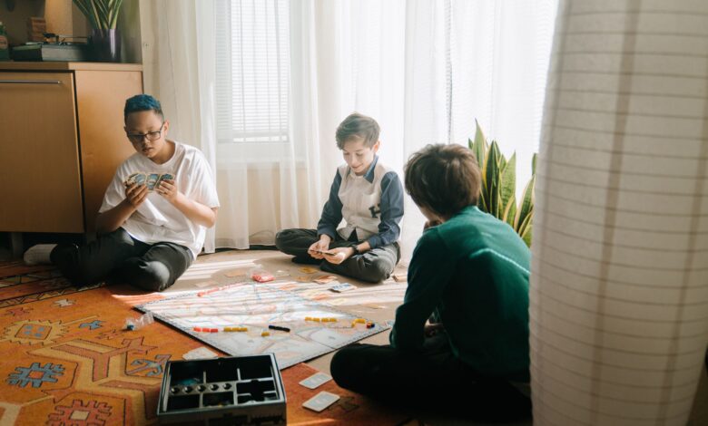 Three boys playing a strategic board game in a cozy indoor setting, emphasizing friendship and fun.