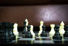 Close-up view of a chess game in progress with black and white pieces in focus on a board.
