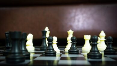 Close-up view of a chess game in progress with black and white pieces in focus on a board.