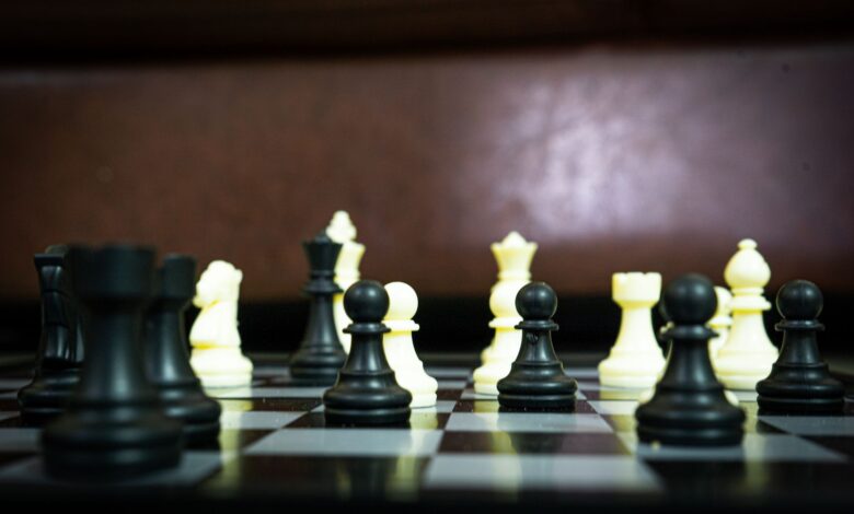 Close-up view of a chess game in progress with black and white pieces in focus on a board.