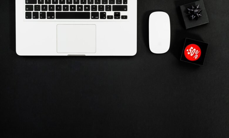 Minimalist flat lay featuring a laptop and shopping items with 50% sale tags.