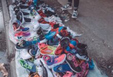 An array of vibrant sneakers displayed by a street vendor on a city pavement.