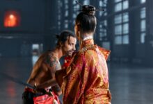 A dramatic scene of martial artists in traditional Japanese attire poised in confrontation within an industrial setting.