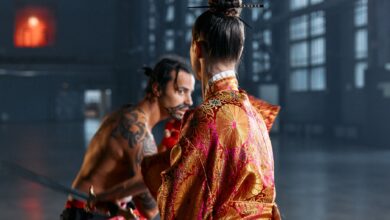 A dramatic scene of martial artists in traditional Japanese attire poised in confrontation within an industrial setting.