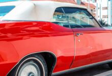 Vibrant red classic car parked in sunny Miami, Florida with urban backdrop.