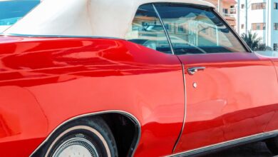 Vibrant red classic car parked in sunny Miami, Florida with urban backdrop.