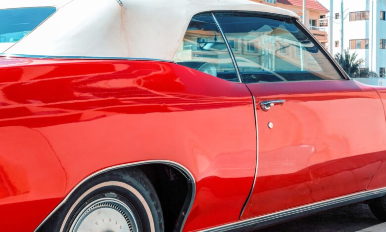 Vibrant red classic car parked in sunny Miami, Florida with urban backdrop.