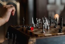An intense moment captured during a chess game, featuring a poised hand above a detailed chessboard.