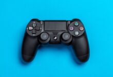 Black game controller against a vibrant blue background, perfect for gaming-themed content.