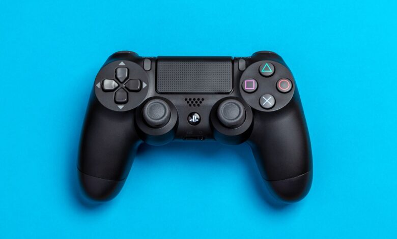Black game controller against a vibrant blue background, perfect for gaming-themed content.