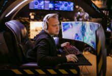 A focused gamer using an advanced multi-monitor setup in a modern gaming chair.