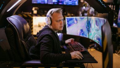 A focused gamer using an advanced multi-monitor setup in a modern gaming chair.