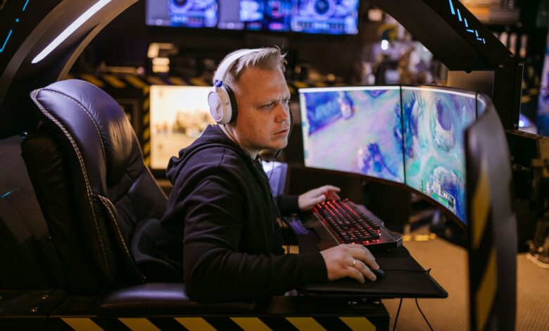 A focused gamer using an advanced multi-monitor setup in a modern gaming chair.
