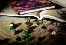 Close-up of tabletop RPG setup with books, dice, and figurines on a map.