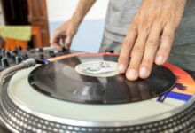 Close-up of a DJ using a turntable to mix vinyl records indoors.