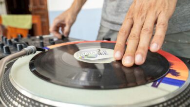 Close-up of a DJ using a turntable to mix vinyl records indoors.