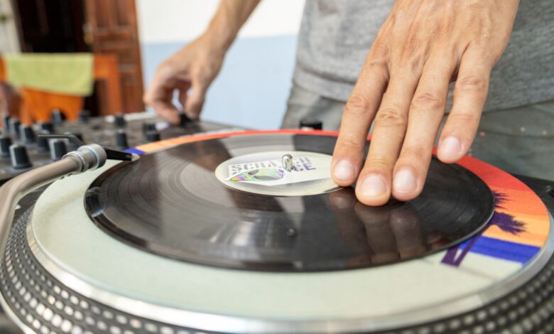 Close-up of a DJ using a turntable to mix vinyl records indoors.