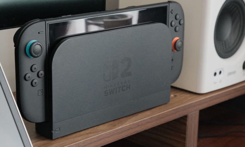 Nintendo console docked among speakers and a monitor on a wooden shelf.