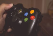 Close-up image of a hand holding a gaming controller with colorful buttons.