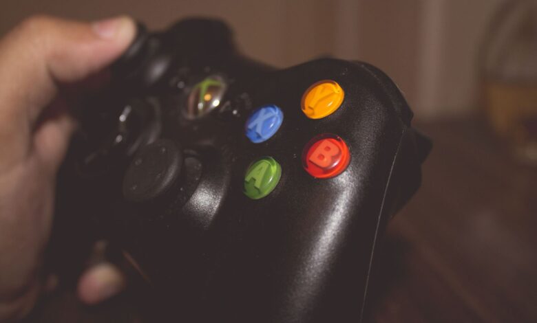 Close-up image of a hand holding a gaming controller with colorful buttons.