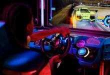 A person playing an immersive arcade racing game with vibrant lights.