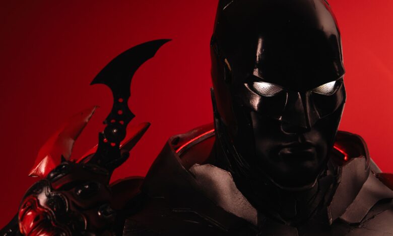 Dramatic portrayal of Batman cosplay against a vivid red backdrop, emphasizing iconic details.