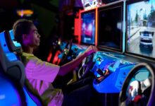 A young man intensely plays a car racing video game at an amusement arcade.