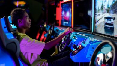 A young man intensely plays a car racing video game at an amusement arcade.