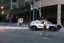 A woman crosses a city street with a Toronto police vehicle nearby.