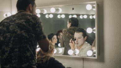 Actors applying makeup backstage in illuminated dressing room before a performance.