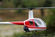 A detailed view of a red remote-controlled helicopter flying outdoors.