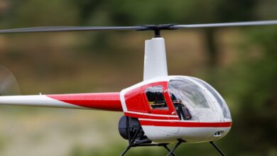 A detailed view of a red remote-controlled helicopter flying outdoors.