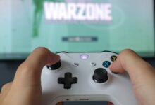 A close-up of hands holding an Xbox controller against a game screen, highlighting the gaming experience.