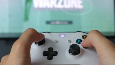 A close-up of hands holding an Xbox controller against a game screen, highlighting the gaming experience.