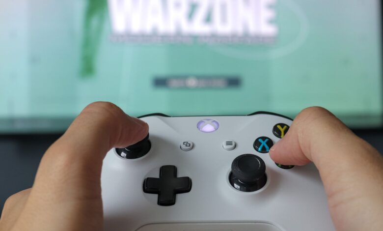 A close-up of hands holding an Xbox controller against a game screen, highlighting the gaming experience.