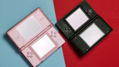 Pink and black Nintendo DS consoles displayed on contrasting red and blue backgrounds.