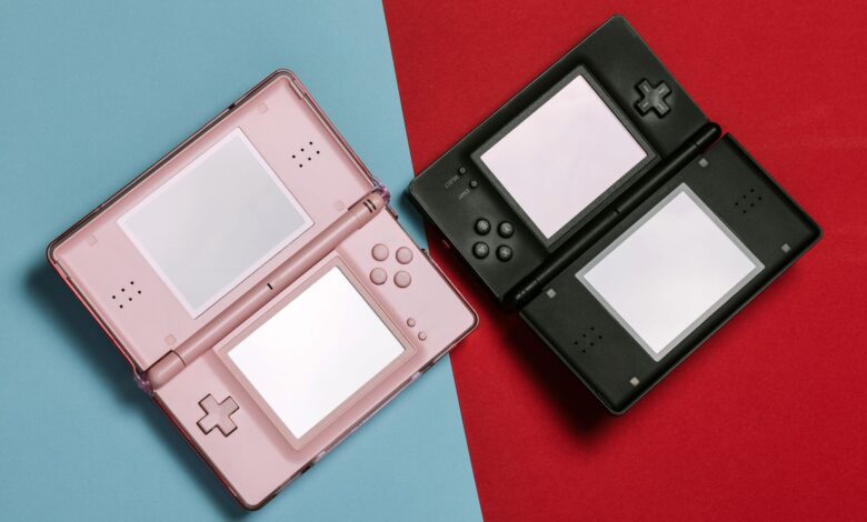 Pink and black Nintendo DS consoles displayed on contrasting red and blue backgrounds.