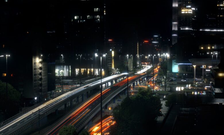 Night view of a bustling highway in Warsaw, Poland, featuring light trails and urban skyscrapers.