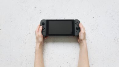 Top view of hands holding a portable gaming console against a textured white background.