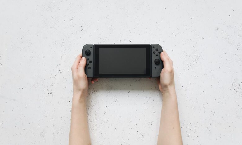Top view of hands holding a portable gaming console against a textured white background.
