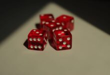 Five red dice with white dots photographed on a neutral background.