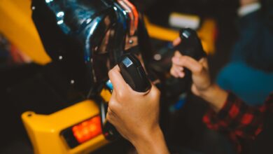 Close-up shot of hands gripping arcade game controllers, showcasing an immersive gaming experience indoors.