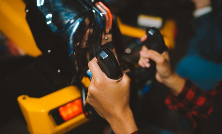 Close-up shot of hands gripping arcade game controllers, showcasing an immersive gaming experience indoors.