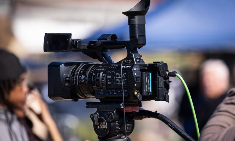 Close-up of a professional video camera set up for filming outdoors, capturing dynamic scenes in natural light.