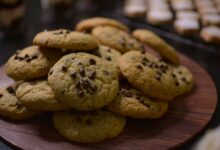 Close-up view of freshly baked chocolate chip cookies on a wooden tray.